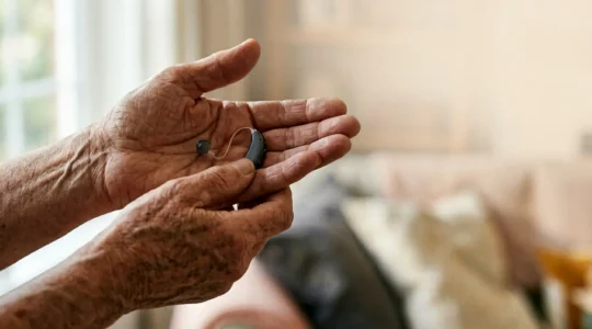 Personne senior tenant un appareil auditif moderne avec expression sereine et confiante